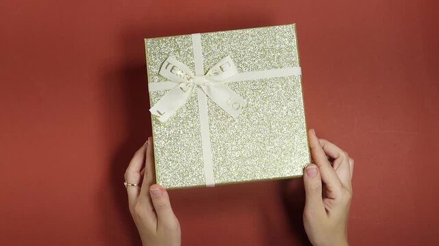 woman opening a golden sparkle gift box contains dried petals