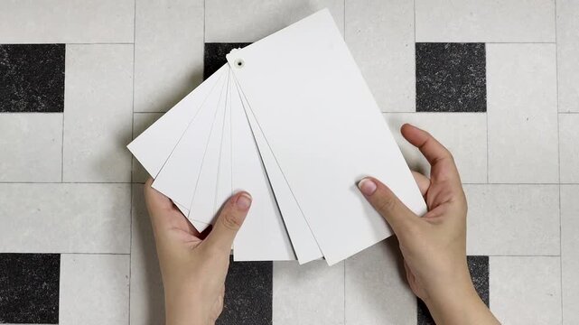 A set of blank white cards arranged in a fan on a pale tiled floor creates a clean, minimalist backdrop ideal for design, stationery layouts, invitations, or calligraphy concepts