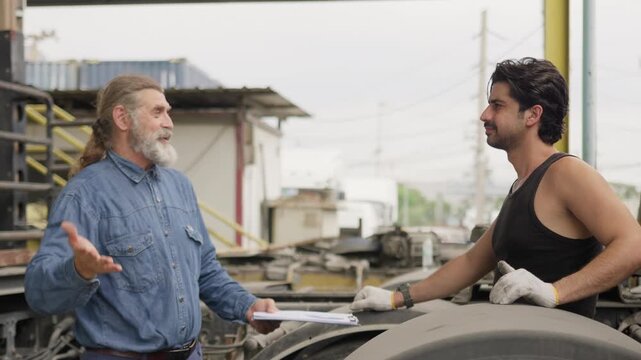Two mechanics celebrate with a high-five after completing a successful vehicle inspection, showcasing teamwork and achievement in a logistics transport hub.