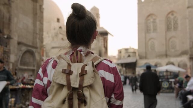 Woman traveler exploring walking through tourist shopping street Khan El Khalili bazaar Cairo market in evening, blurred background