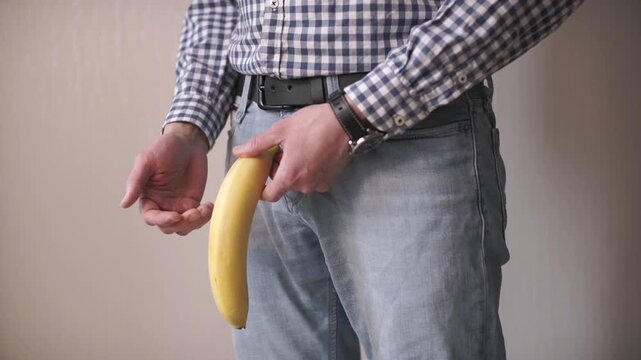 a man holds a banana in the groin area. Problems with the prostate. Age intimate problems of men.