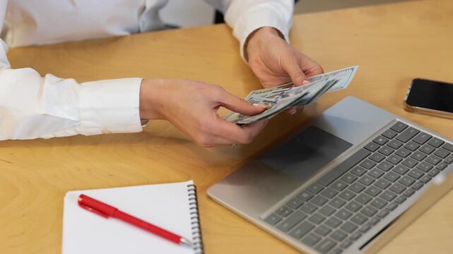 Real-time video, close-up, hand, fingers, money. Caucasian females hands with good nude manicures are counting cash money in front of the computer