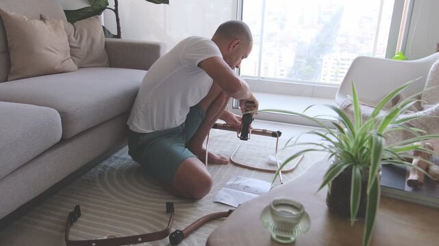 Expectant father carefully assembling a rocking chair for his newborn baby in the living room