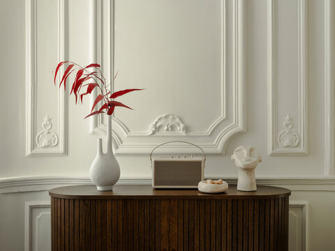 Elegant interior decor with red foliage in a white vase on a dark wood cabinet against a classic paneled wall for sophisticated design