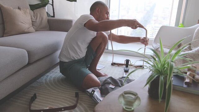 Future dad assembling a newborn bouncer chair in the living room while preparing for the baby's arrival