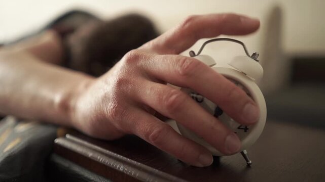 Fatigue man in bed with alarm clock waking him up due to burnout and fatigue in the bedroom.