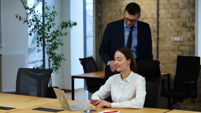Realtime video. Caucasian woman is working on computer, man is coming to room putting envelope with money on her desk, and she is exiting.