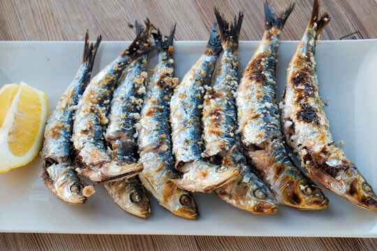 Grilled sardines with lemon on white plate