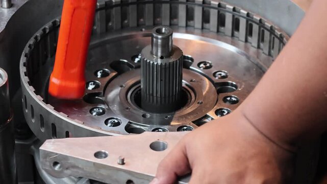 A close-up, static shot of a mechanic using a rubber dead blow hammer to carefully seat a piston into its housing. The footage demonstrates professional manual assembly.