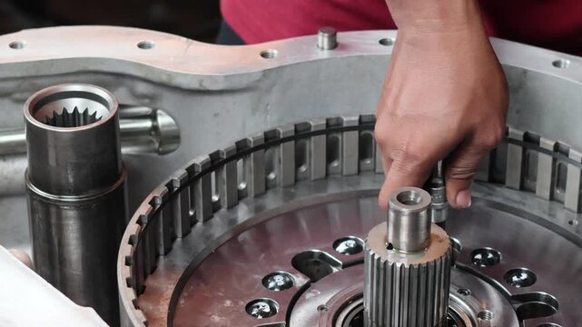 A professional static shot of a mechanic's hand using a hex key socket to tighten bolts inside a heavy-duty industrial gearbox.