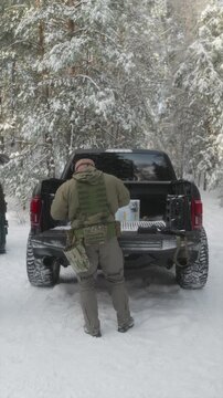 Soldier in multicam gear preparing near pickup truck in winter field