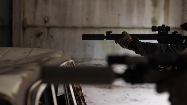 Two tactical soldiers firing rifles inside industrial hangar facility