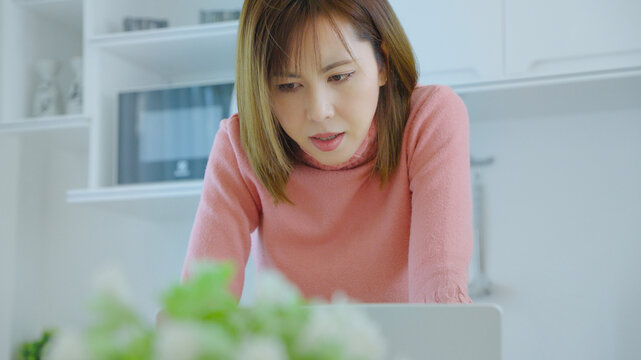 Young woman concentrating on laptop in bright home office with cozy atmosphere and minimal modern background