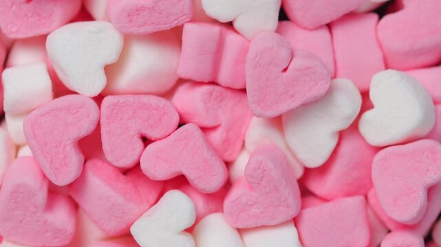 Pile of pink and white heart shaped marshmallows rotating.  Top view shot.