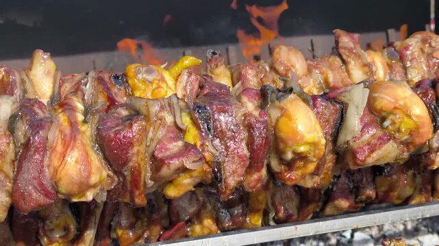 Delicious mixed meat cooking on rotisserie skewers over fire