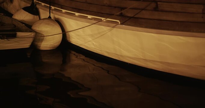 Boat hull with fenders and water reflections at night
