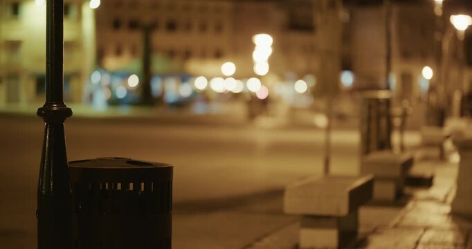 Street with benches and lamp post illuminated at night