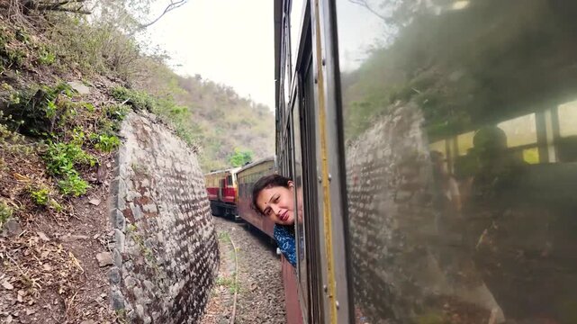A happy traveler leans out of a train window smiling.