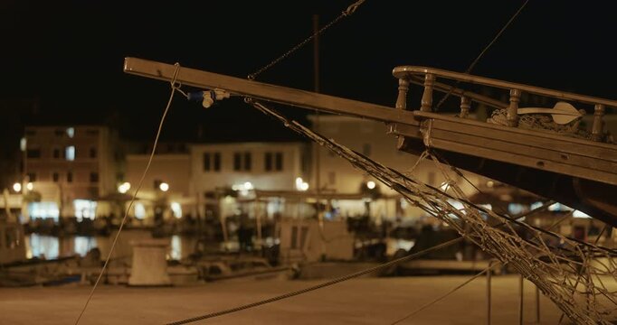 Wooden boat bow with ropes at waterfront at night
