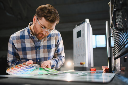 Print worker checking colors with swatches on press