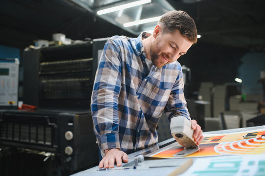 Print factory worker checking color quality on sheet