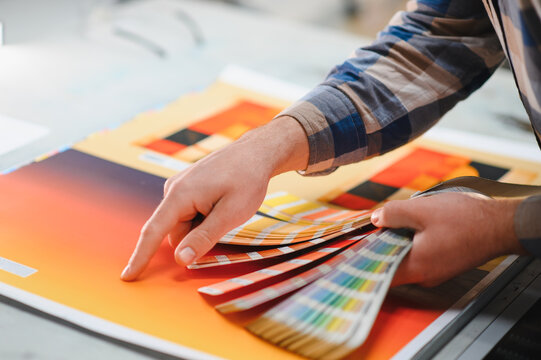 Man's hand matching colors with a swatch book