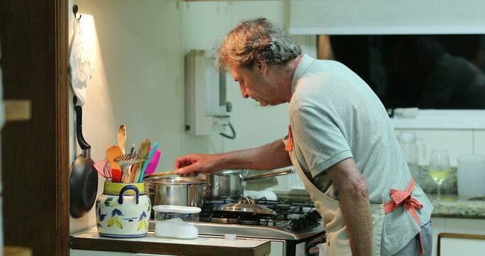 Older senior man cooking at the kitchen, candid chef