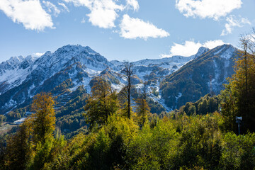 Obraz premium Mountains stand tall under blue sky with clouds in the distance and trees in the foreground