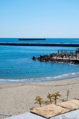 Fototapeta premium Serene sandy beach with blue ocean and distant pier on a sunny day.