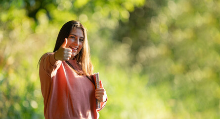 Fototapeta premium Happy student giving thumbs up in park