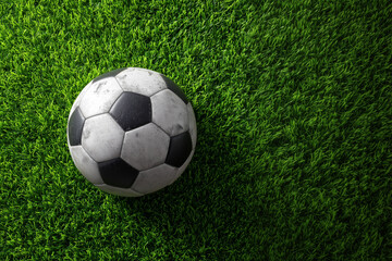 Fototapeta premium Top View of Classic Black and White Soccer Ball on Vibrant Green Grass with Copy Space