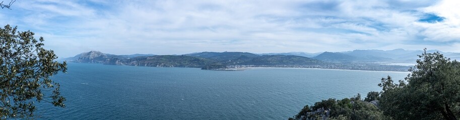 Fototapeta premium Panoramic view showing the bay, coastline, town, and mountains under a blue sky laredo cantabria spain