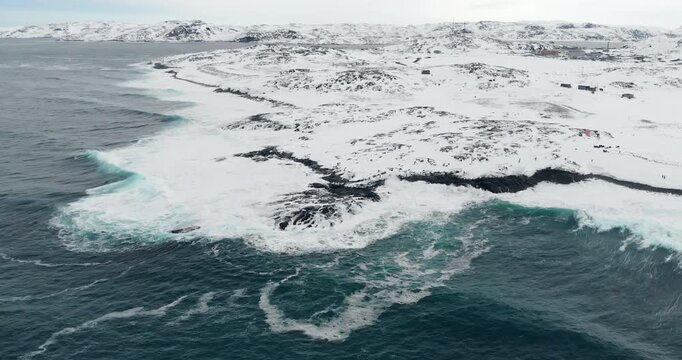 A sweeping aerial panorama shows the frozen coastline and open sea stretching into the distance.