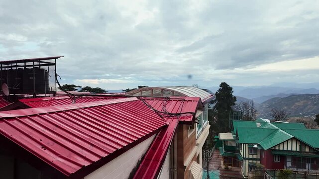 A picturesque view of red roofs and distant mountains from a window.