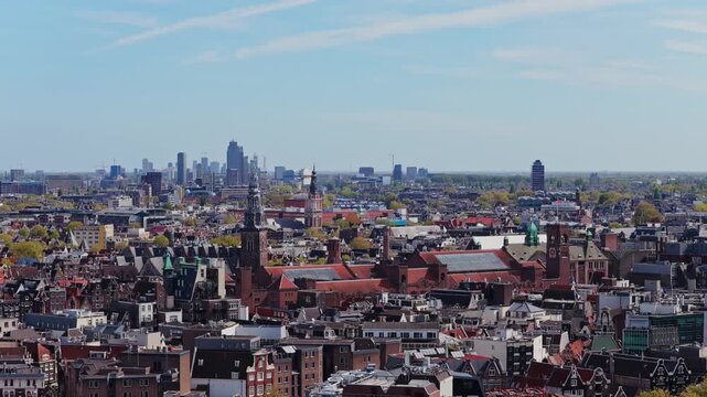 Aerial survey flying over Amsterdam showing Beurs van Berlage, Oude Kerk, Basilica of Saint Nicholas, Zuidas business district against blue spring sky on sunny day