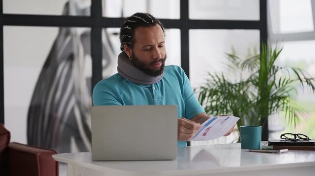 Black man in a cervical neck collar reading an overdue health insurance letter