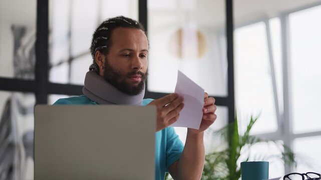 Man in cervical neck collar reading hospital bill letter, shocked by high costs