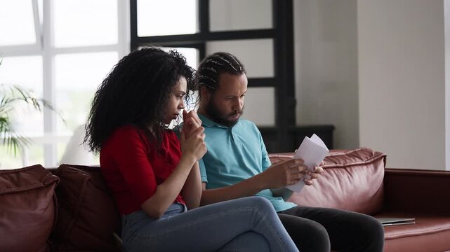 Young Black couple reading a bad news letter, stressed about a rejected visa