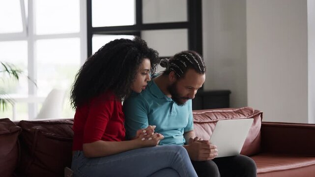 African American couple receiving a good news email at home, celebrating success