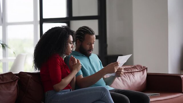African American couple reading a letter, shocked by bad news, job rejection