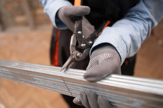 construction worker uses cutting scissors for metal drywall profiles