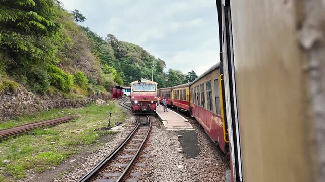 Two trains pass on a curved mountain railway track.