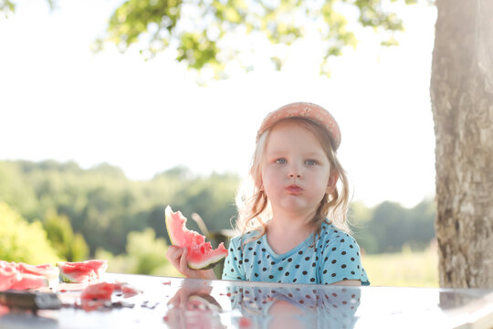cute little girl eating watermelon outdoors in summertime. Child and watermelon in summer. 