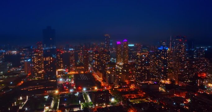 Wide Jersey City night skyline with river haze. Wide aerial of Jersey City skyline, street grids, tower lights, Hudson River haze and dark sky.