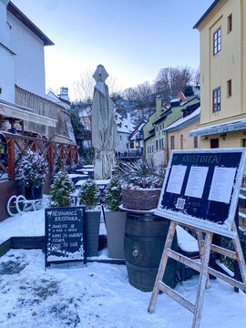 VItava river and the white snowy, fairy tale village, houses, castle and tower covered by snow in winter in Cesky Krumlov, Czechia 