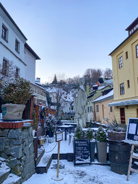 VItava river and the white snowy, fairy tale village, houses, castle and tower covered by snow in winter in Cesky Krumlov, Czechia 