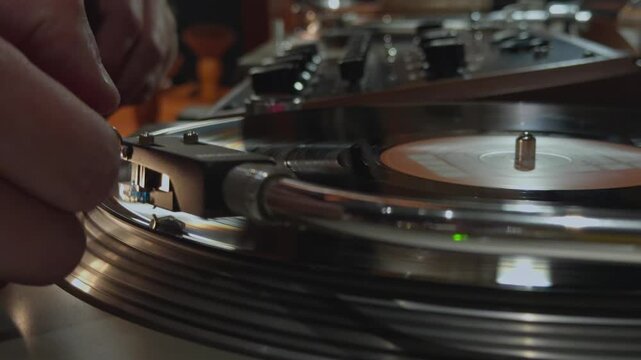 close-up of a vinyl record player with a rotating vinyl record, a tonearm with a pickup needle, DJ hands changing the record, remote control, bar