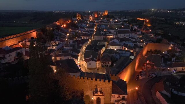 Obidos Illuminated Skyline, Aerial View at Night in Leiria, Portugal. Medieval Building In Famous District Of City.