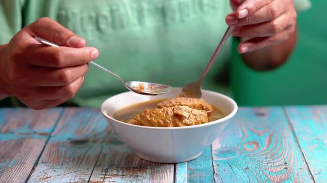 Indonesian is eating bakso gajah (bakso jumbo, giant meat ball). Bakso is one of indonesian street food.