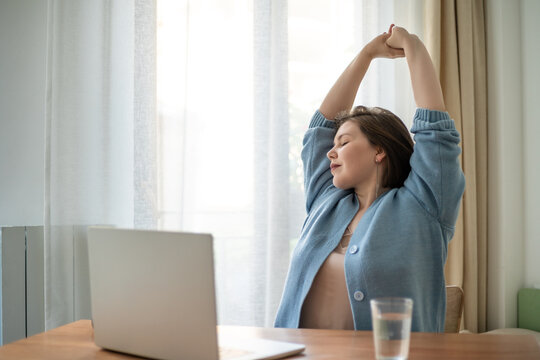 Work break plus size woman stretching arms by laptop, home office wellness, ergonomic rest, self care, healthy routine, body positive lifestyle.